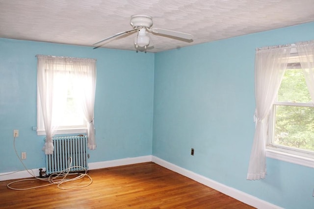 49 Newcomb Rd, Stoneham, MA 02180 - empty room featuring radiator, healthy amount of natural light, ceiling fan, wood finished floors, and a textured ceiling