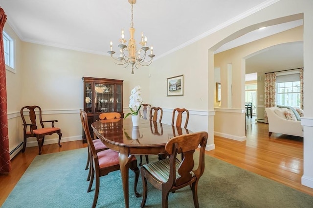 dining space with crown molding, a baseboard heating unit, hardwood / wood-style floors, and an inviting chandelier