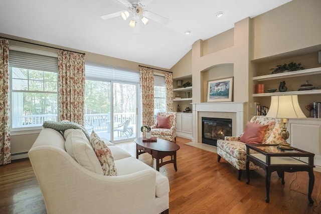 living room featuring hardwood / wood-style flooring, built in features, ceiling fan, baseboard heating, and high vaulted ceiling