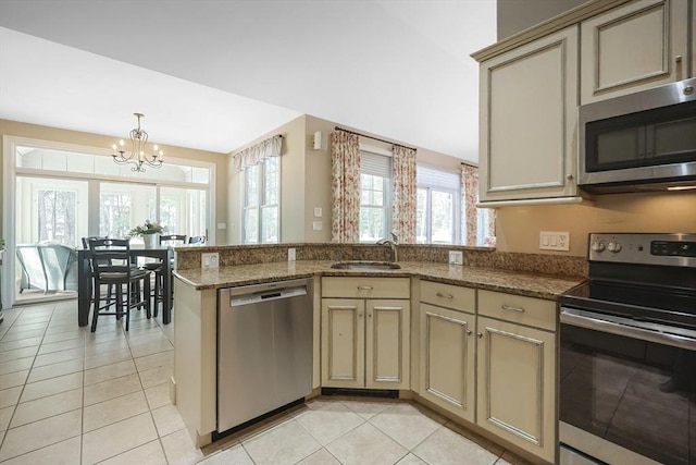 kitchen featuring sink, light tile patterned flooring, kitchen peninsula, and appliances with stainless steel finishes