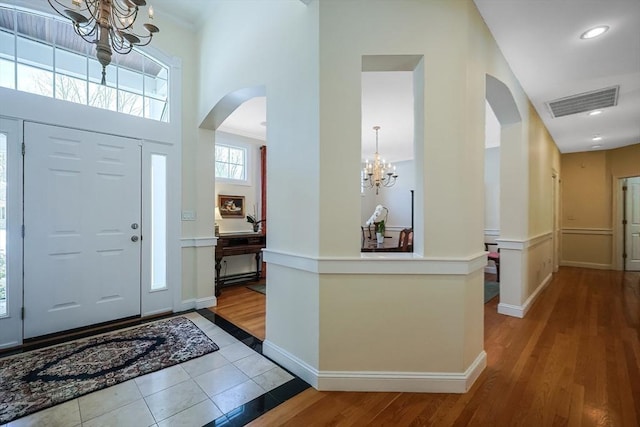 tiled foyer featuring a high ceiling, ornamental molding, and a chandelier