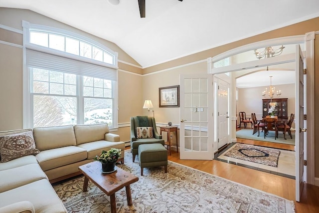 living room with hardwood / wood-style flooring, vaulted ceiling, a baseboard heating unit, and an inviting chandelier