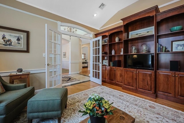 interior space with lofted ceiling, ornamental molding, french doors, and light wood-type flooring