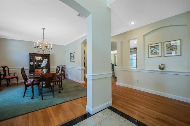 dining area featuring crown molding, an inviting chandelier, and light hardwood / wood-style floors