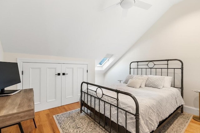 bedroom featuring lofted ceiling, light wood-type flooring, a closet, ceiling fan, and a skylight