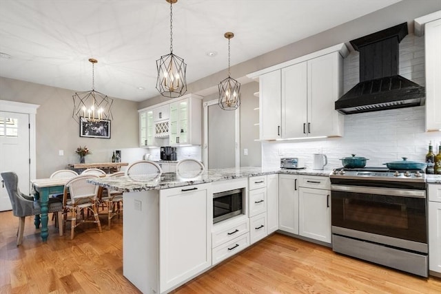 kitchen featuring stainless steel appliances, wall chimney exhaust hood, a peninsula, and white cabinetry