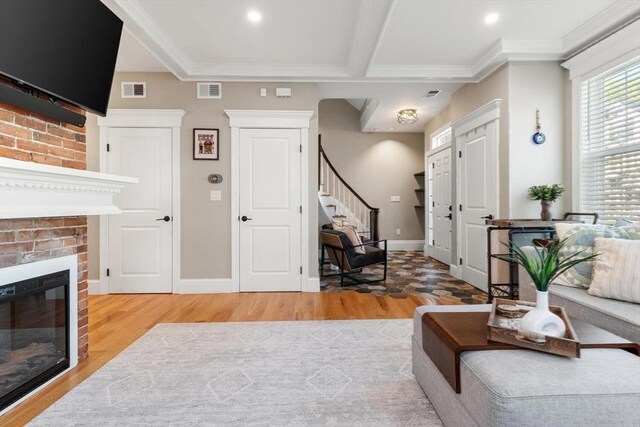 living area with light wood-style flooring, stairs, a fireplace, crown molding, and baseboards