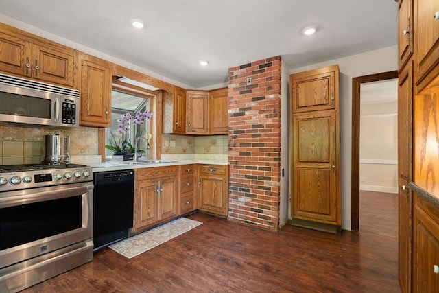 23 Hanson St, Wakefield, MA 01880 - kitchen with stainless steel appliances, a sink, light countertops, brown cabinetry, and backsplash