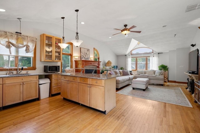 23 Hanson St, Wakefield, MA 01880 - kitchen featuring stainless steel microwave, a sink, lofted ceiling, light wood-type flooring, and a fireplace
