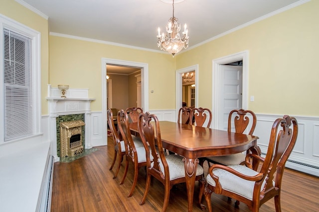 dining room with a baseboard heating unit, dark hardwood / wood-style floors, ornamental molding, and a notable chandelier