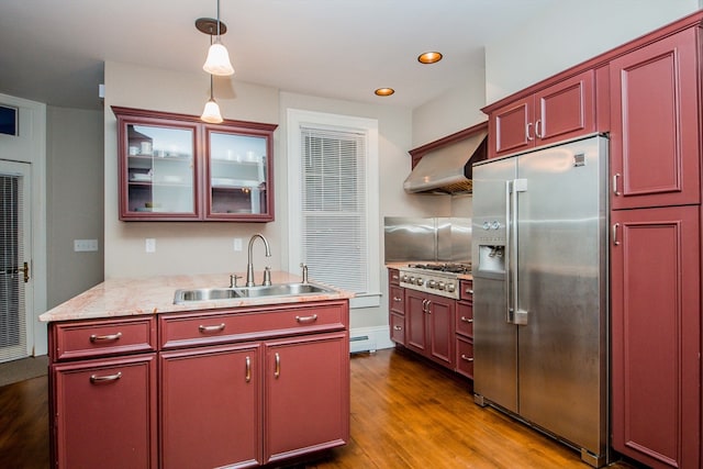 kitchen with sink, wall chimney exhaust hood, dark wood-type flooring, stainless steel appliances, and pendant lighting