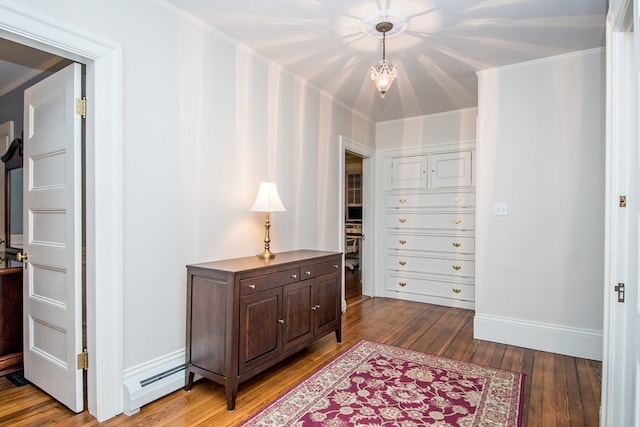 interior space with wood-type flooring, crown molding, and a baseboard heating unit