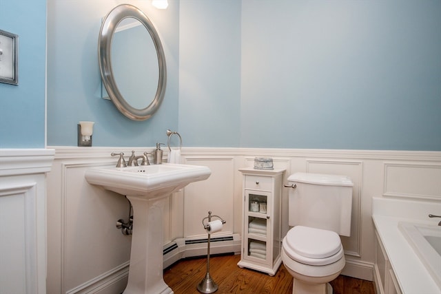 bathroom featuring a washtub, wood-type flooring, a baseboard radiator, and toilet