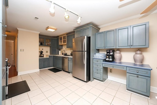 kitchen with light tile patterned floors, crown molding, built in desk, and stainless steel appliances