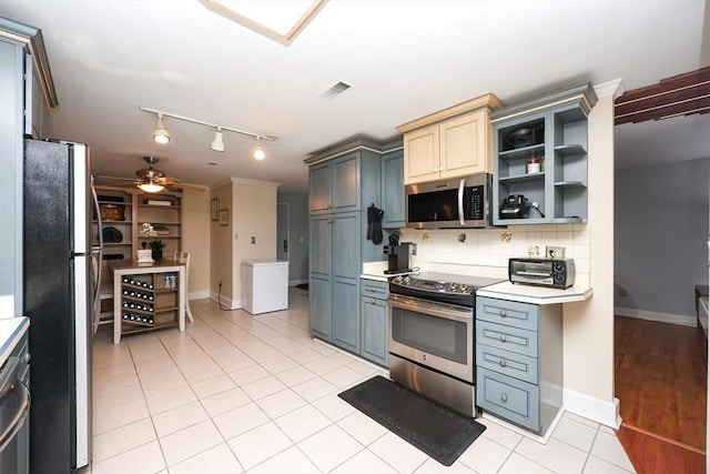 kitchen with light tile patterned flooring, appliances with stainless steel finishes, gray cabinets, and decorative backsplash