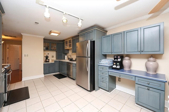 kitchen with light tile patterned floors, crown molding, built in desk, and stainless steel appliances