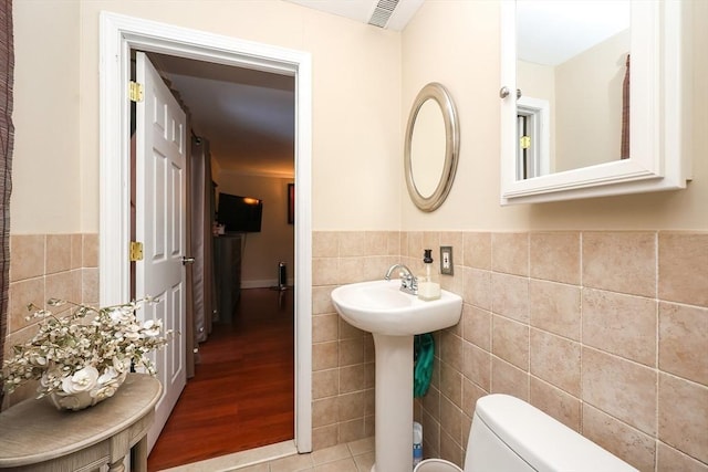 bathroom with wood-type flooring, sink, tile walls, and toilet