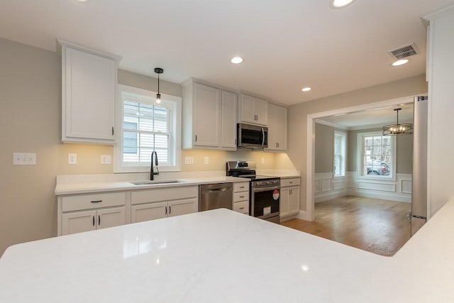 kitchen with a healthy amount of sunlight, visible vents, appliances with stainless steel finishes, a sink, and light wood-style floors