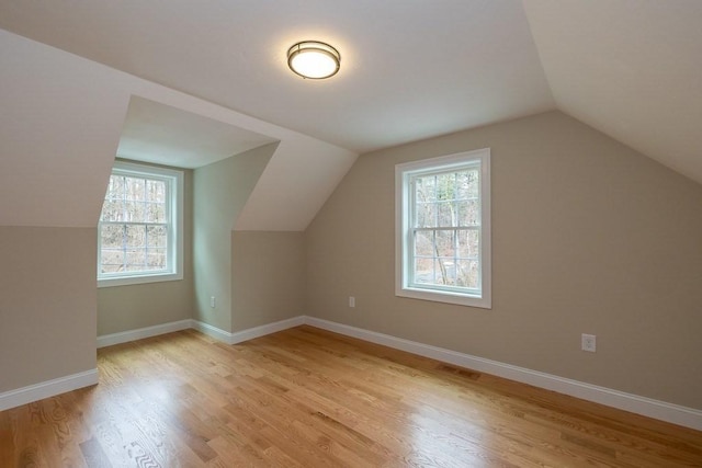 bonus room with light wood-type flooring, baseboards, lofted ceiling, and a wealth of natural light