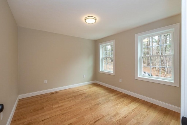 unfurnished room featuring baseboards, light wood finished floors, and visible vents