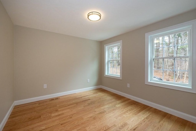 empty room with light wood-type flooring, baseboards, and visible vents