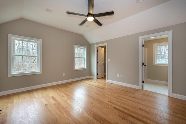 unfurnished bedroom with vaulted ceiling, multiple windows, and light wood-type flooring