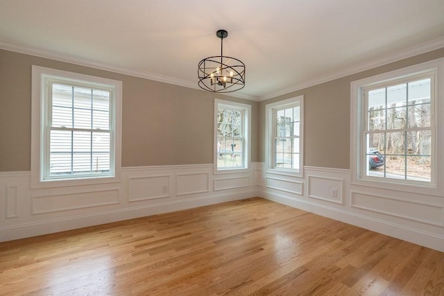 unfurnished dining area featuring a healthy amount of sunlight, crown molding, and a notable chandelier