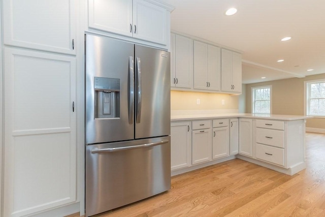 kitchen featuring stainless steel refrigerator with ice dispenser, light wood-type flooring, light countertops, a peninsula, and white cabinetry