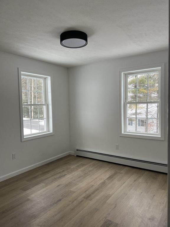 unfurnished room with a baseboard radiator and light wood-type flooring