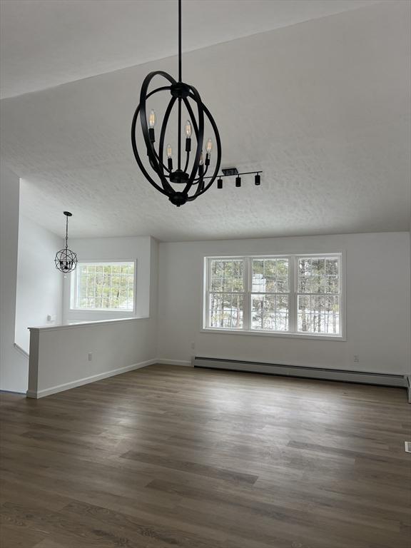 unfurnished living room with an inviting chandelier, a baseboard heating unit, dark hardwood / wood-style floors, and a textured ceiling