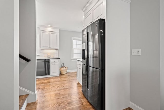 kitchen with stainless steel appliances, white cabinetry, decorative backsplash, and light wood-type flooring