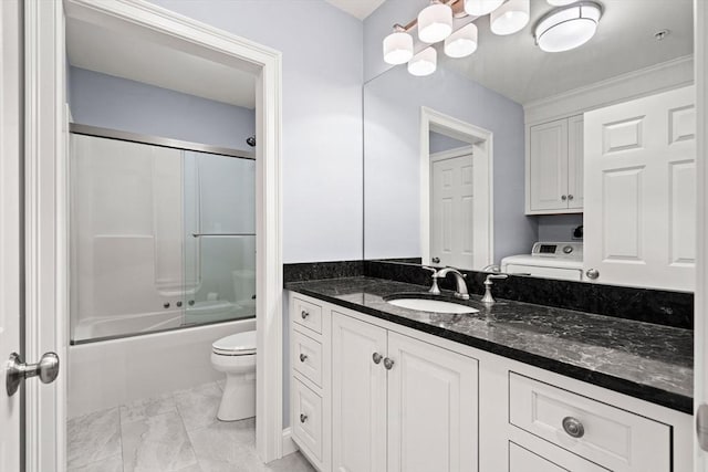 bathroom with washer / dryer, toilet, vanity, shower / bath combination with glass door, and a chandelier