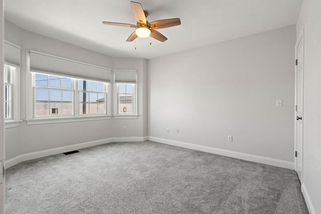 carpeted spare room featuring ceiling fan and baseboards
