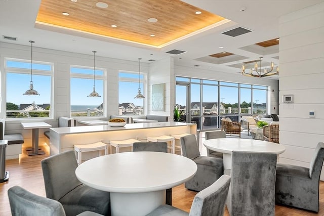 dining room with wood walls, a tray ceiling, wooden ceiling, and light hardwood / wood-style flooring