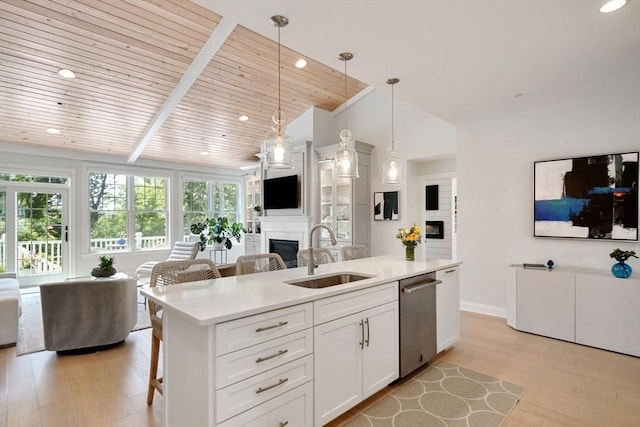 kitchen featuring white cabinetry, sink, hanging light fixtures, stainless steel dishwasher, and a center island with sink