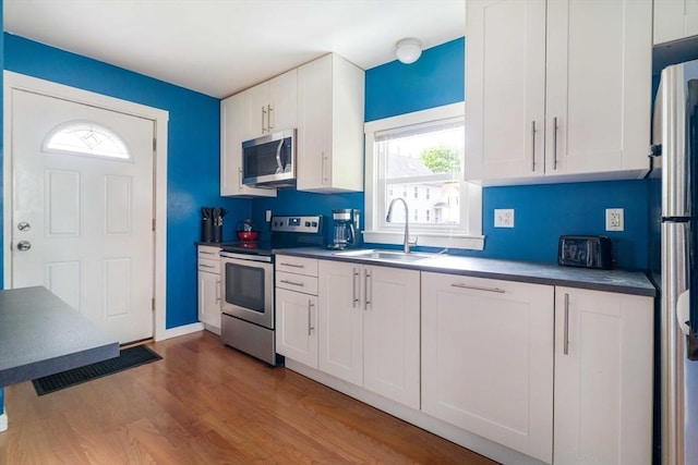 12 Cross St, Pepperell, MA 01463 - kitchen with stainless steel appliances, a sink, wood finished floors, white cabinets, and dark countertops