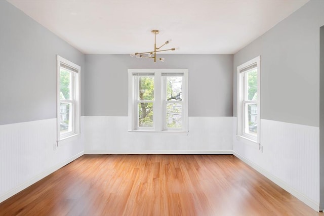 12 Cross St, Pepperell, MA 01463 - unfurnished room featuring wood finished floors, plenty of natural light, a wainscoted wall, and a chandelier