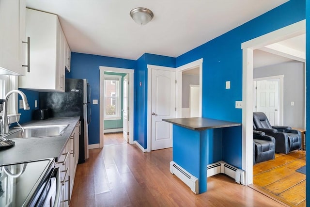 12 Cross St, Pepperell, MA 01463 - kitchen with wood finished floors, a sink, a baseboard heating unit, and white cabinetry