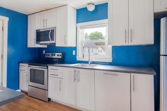 12 Cross St, Pepperell, MA 01463 - kitchen featuring stainless steel appliances, a sink, white cabinets, light wood finished floors, and dark countertops