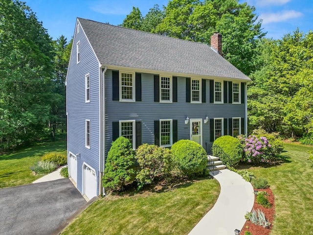 1005 Forest St, North Andover, MA 01845 - colonial house featuring a chimney, a garage, asphalt driveway, a front lawn, and roof with shingles