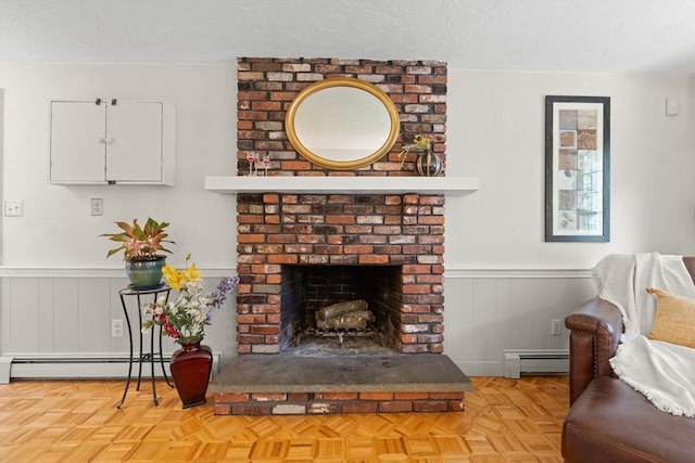 1005 Forest St, North Andover, MA 01845 - living area featuring a baseboard heating unit, a wainscoted wall, a fireplace, a textured ceiling, and a decorative wall