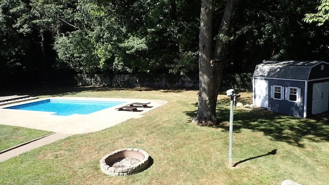 view of swimming pool with an outdoor fire pit, a yard, and a shed