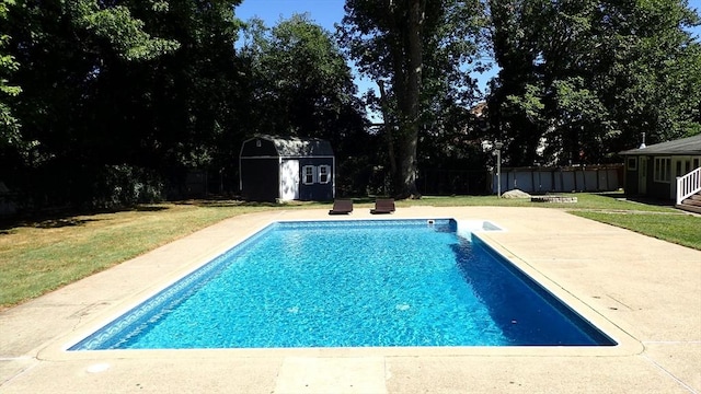 view of swimming pool featuring a lawn, a shed, and a patio area