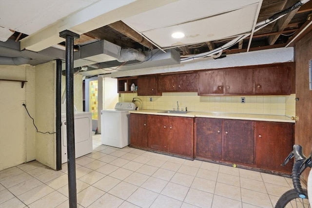 below grade area with light tile patterned floors, a sink, and washer / clothes dryer