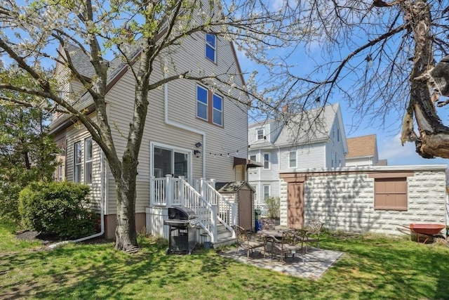 back of house with a storage unit, a patio area, and a lawn