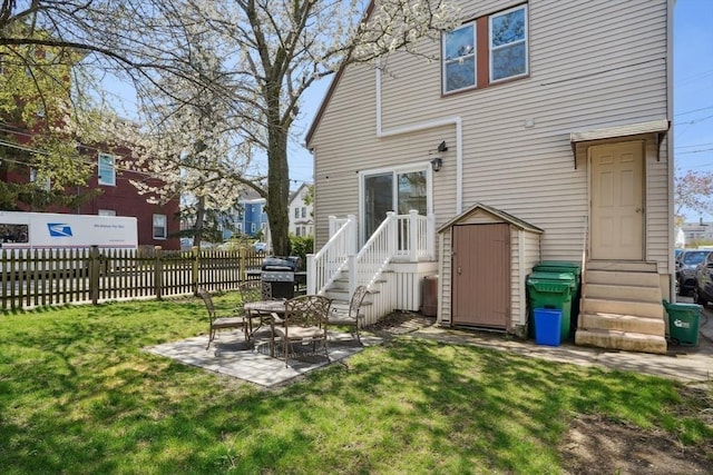 rear view of house with a storage unit, fence, a patio, entry steps, and a lawn