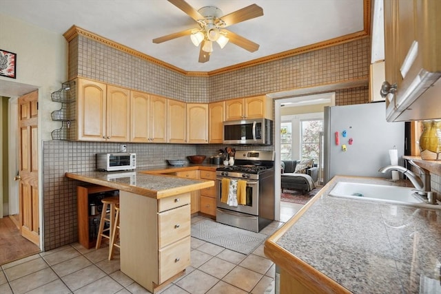 kitchen featuring light brown cabinetry, light tile patterned floors, stainless steel appliances, and a sink