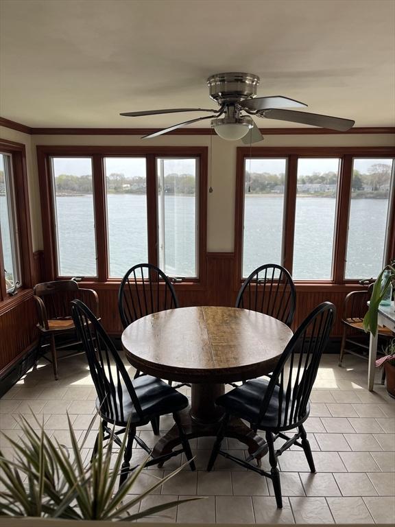 60 Academy Dr, Bourne, MA 02532 - dining room with a water view, a wainscoted wall, a ceiling fan, and wooden walls