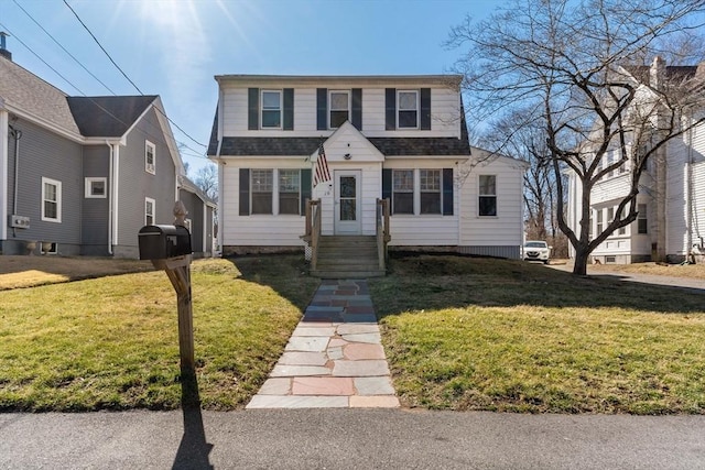 dutch colonial featuring roof with shingles and a front lawn