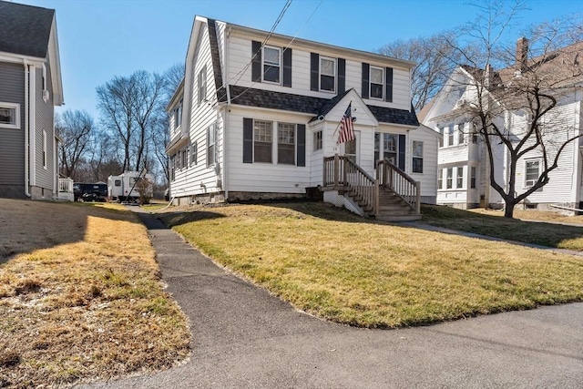 view of front of home with a gambrel roof, a front lawn, and a shingled roof